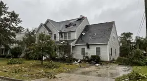 Storm damaged asphalt shingle roof with missing shingles and peeled ridge cap on a Virginia home after a storm